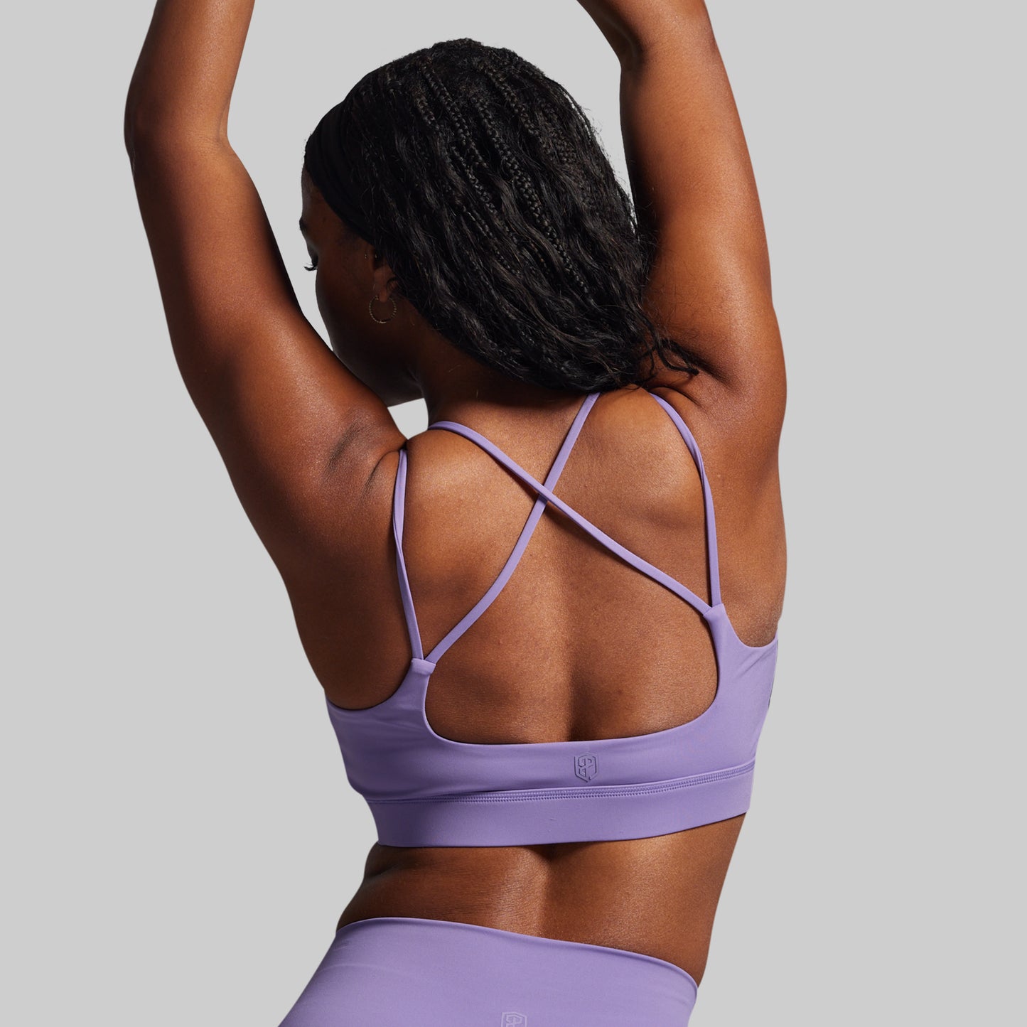 Person wearing a purple sports bra and leggings on a gray background