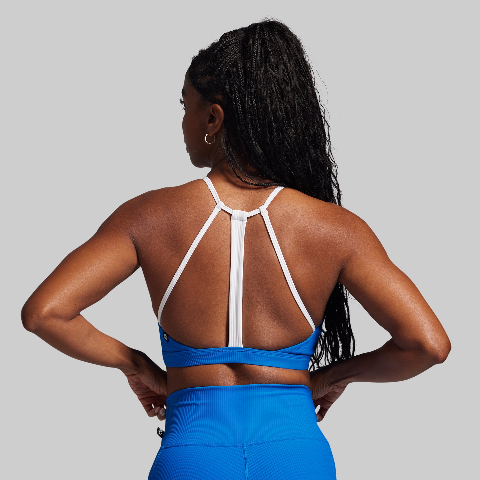 Person wearing a blue sports bra and leggings with a gray background