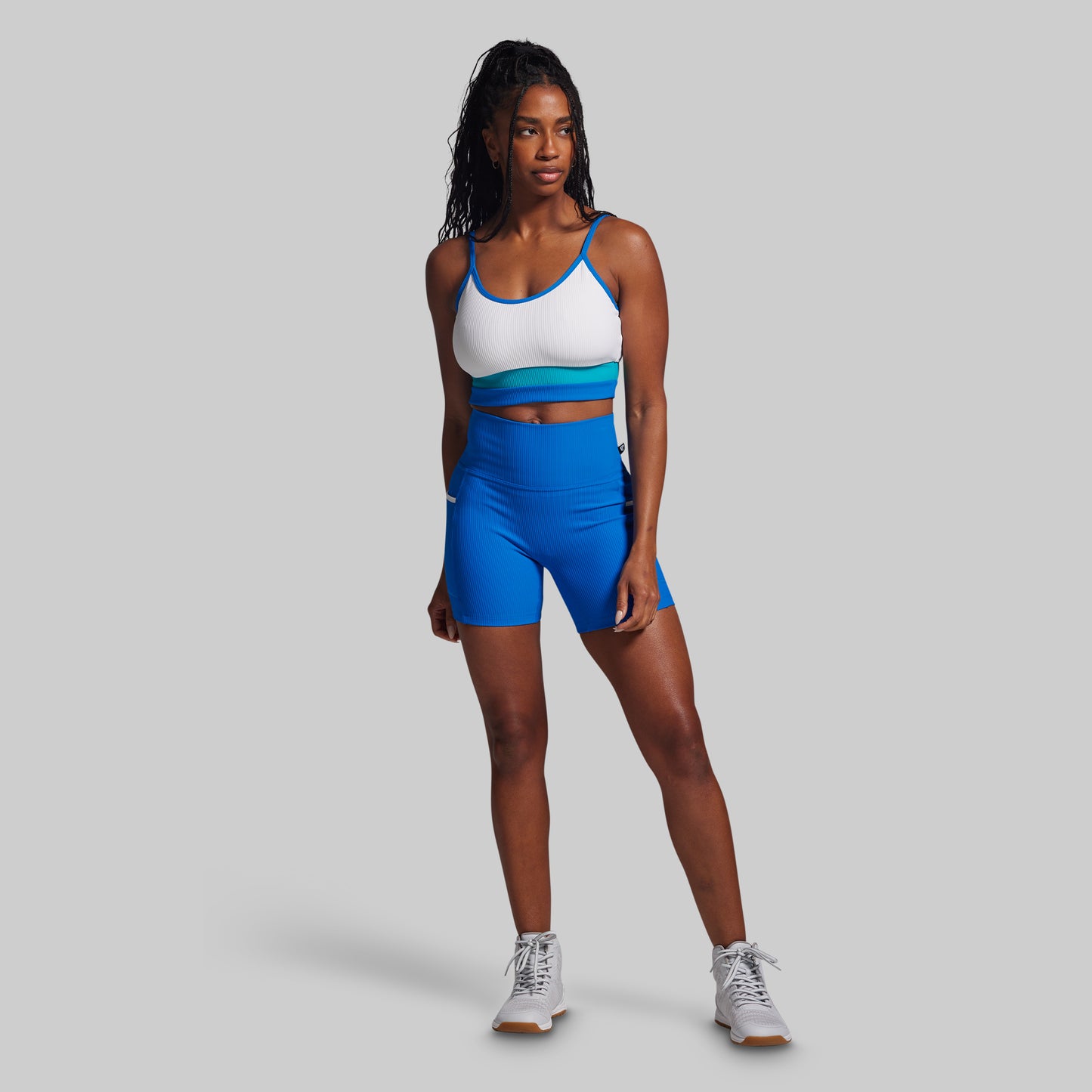 Woman wearing a sports bra and shorts on a gray background