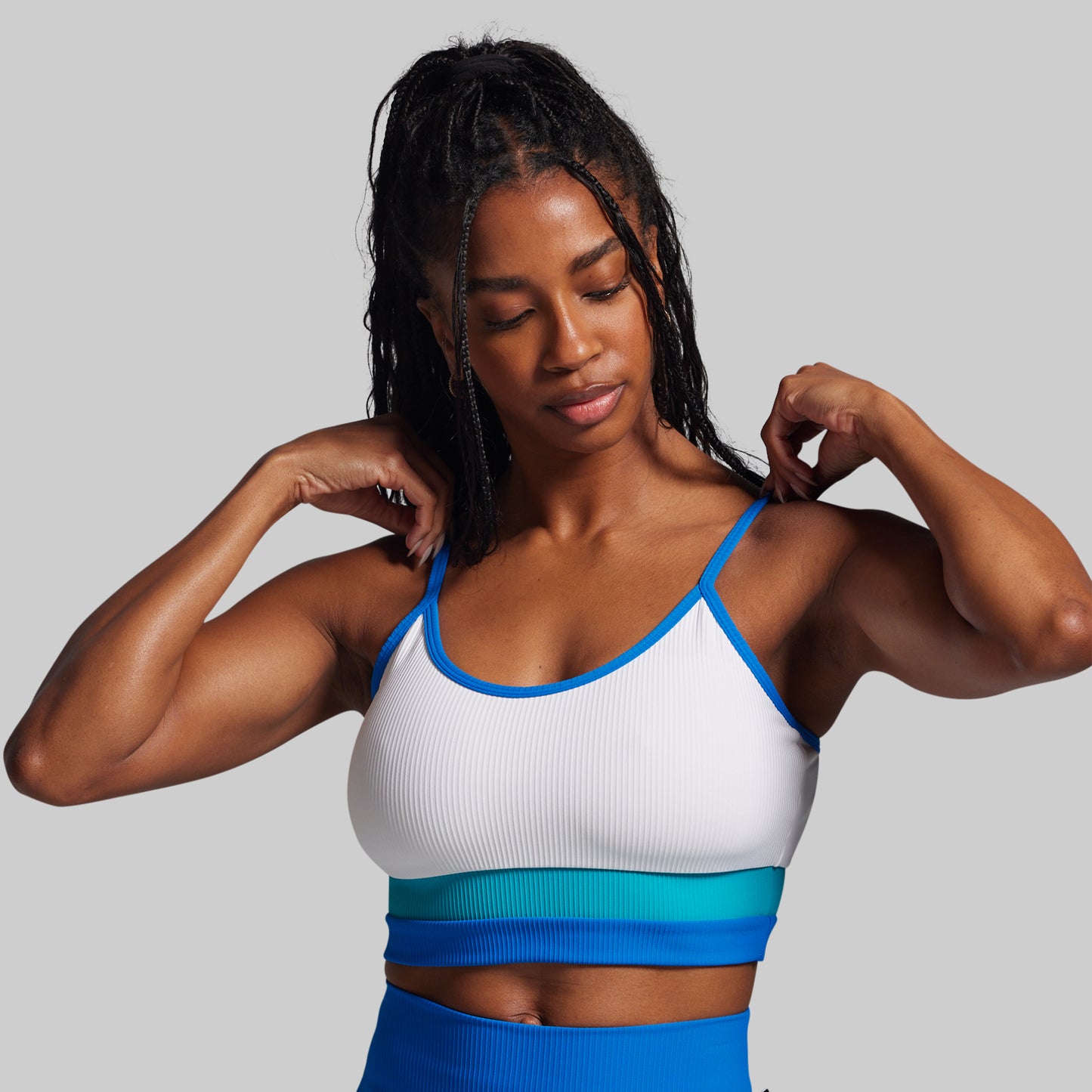Woman wearing a white and blue sports bra and leggings against a gray background