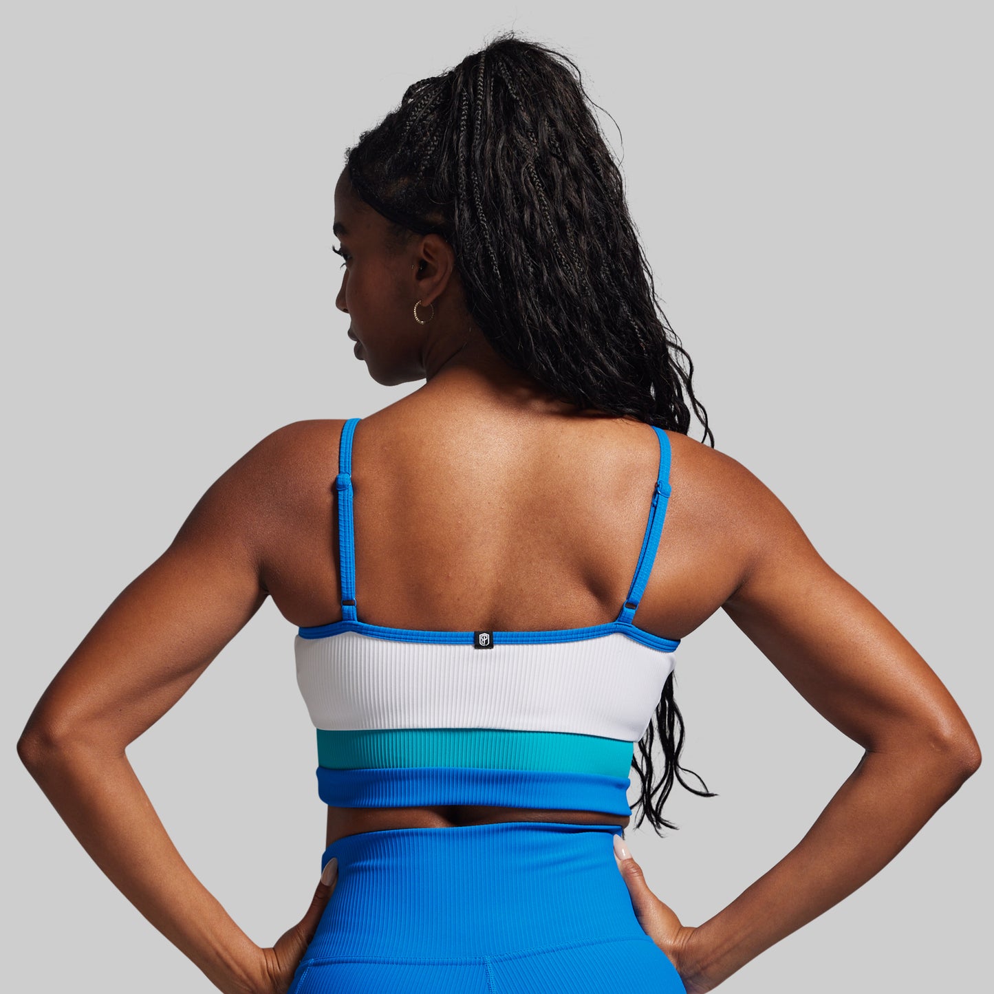 Woman wearing a blue and white sports bra and leggings on a gray background