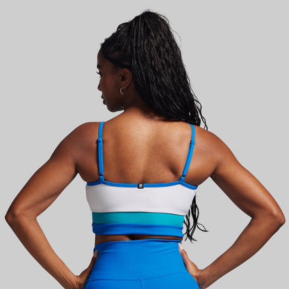 Woman wearing a blue and white sports bra and leggings on a gray background