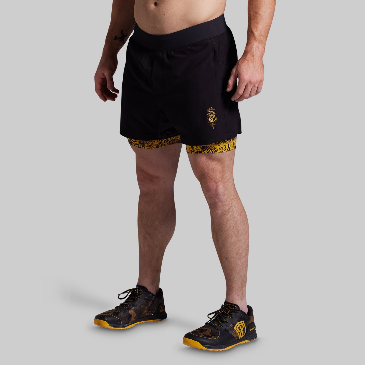 Person wearing black athletic shorts with a logo on a gray background