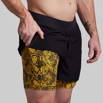 Person wearing black and yellow patterned shorts on a plain background