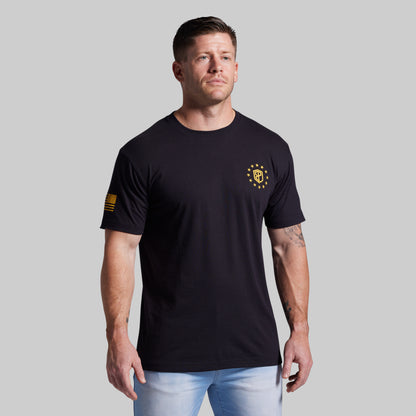 Man wearing a black t-shirt with a logo on a gray background