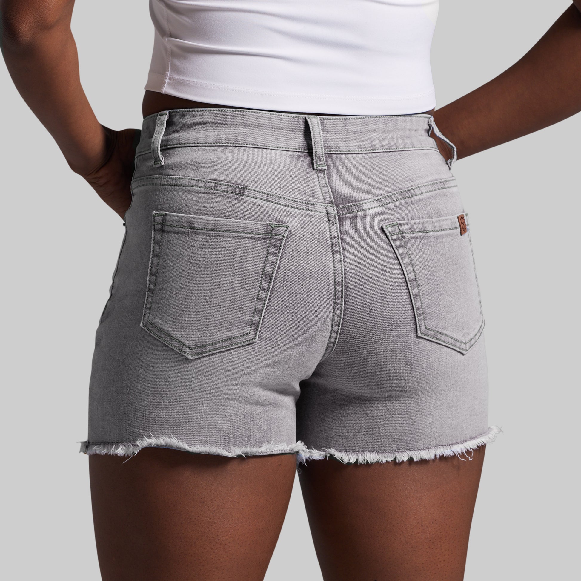 Person wearing gray denim shorts on a plain background