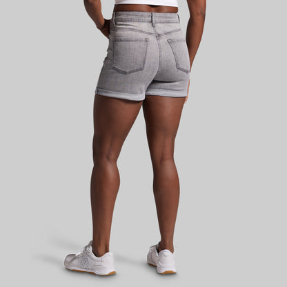 Person wearing gray denim shorts on a plain background