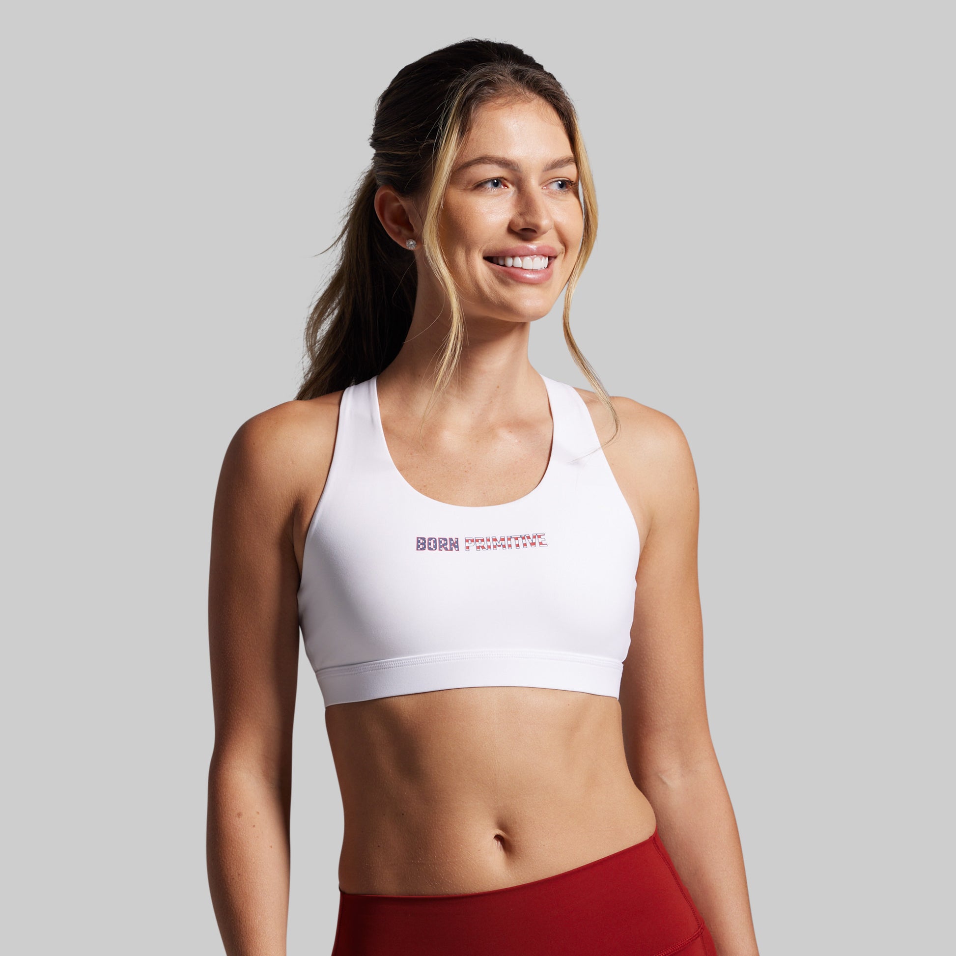Woman wearing a white sports bra with visible branding on a gray background