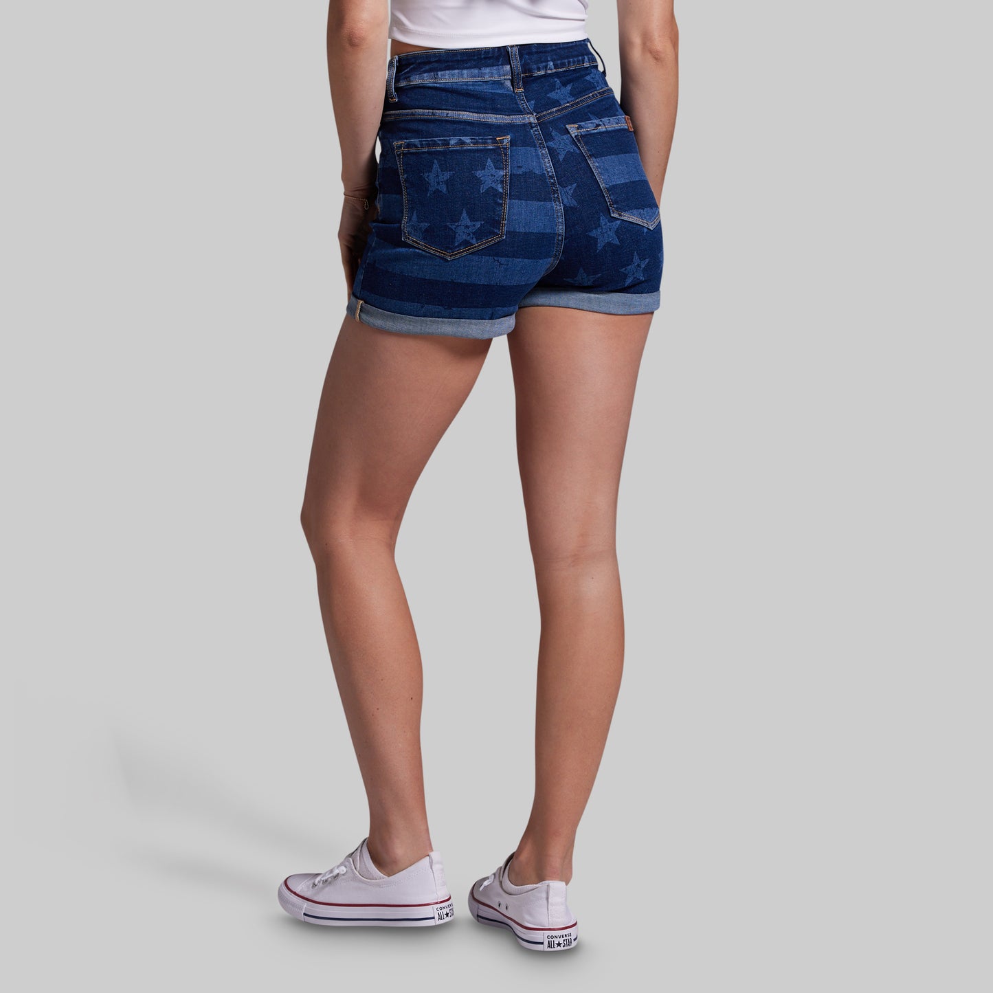Person wearing blue denim shorts with star pattern on a gray background