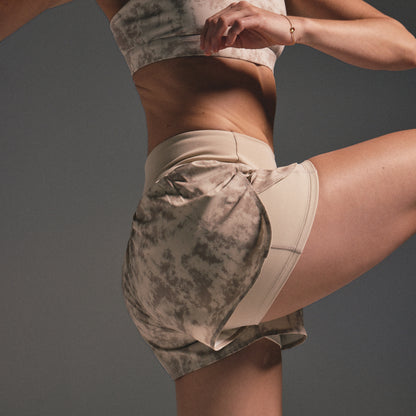 Person wearing tie-dye athletic shorts on a gray background