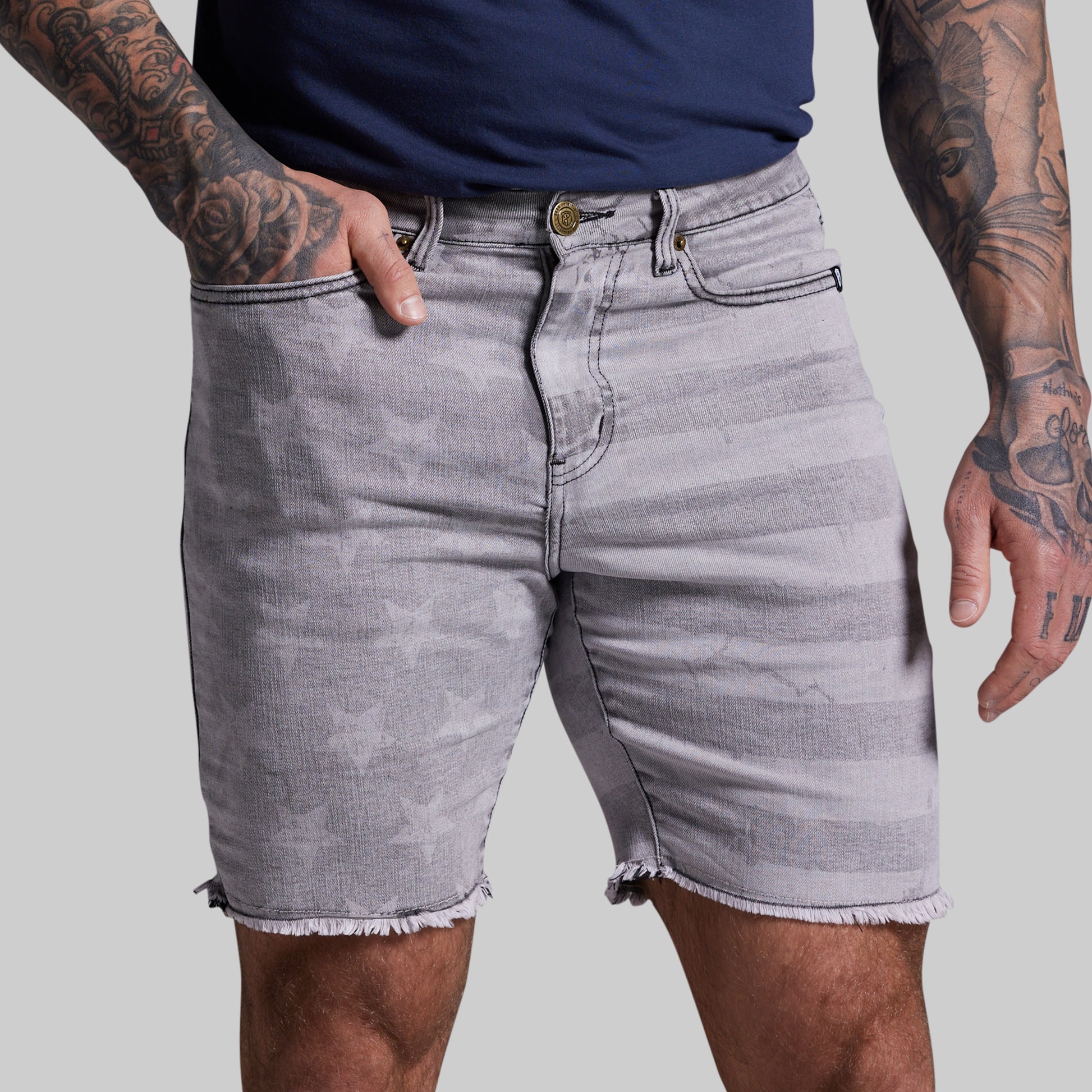 Person wearing gray denim shorts on a plain background