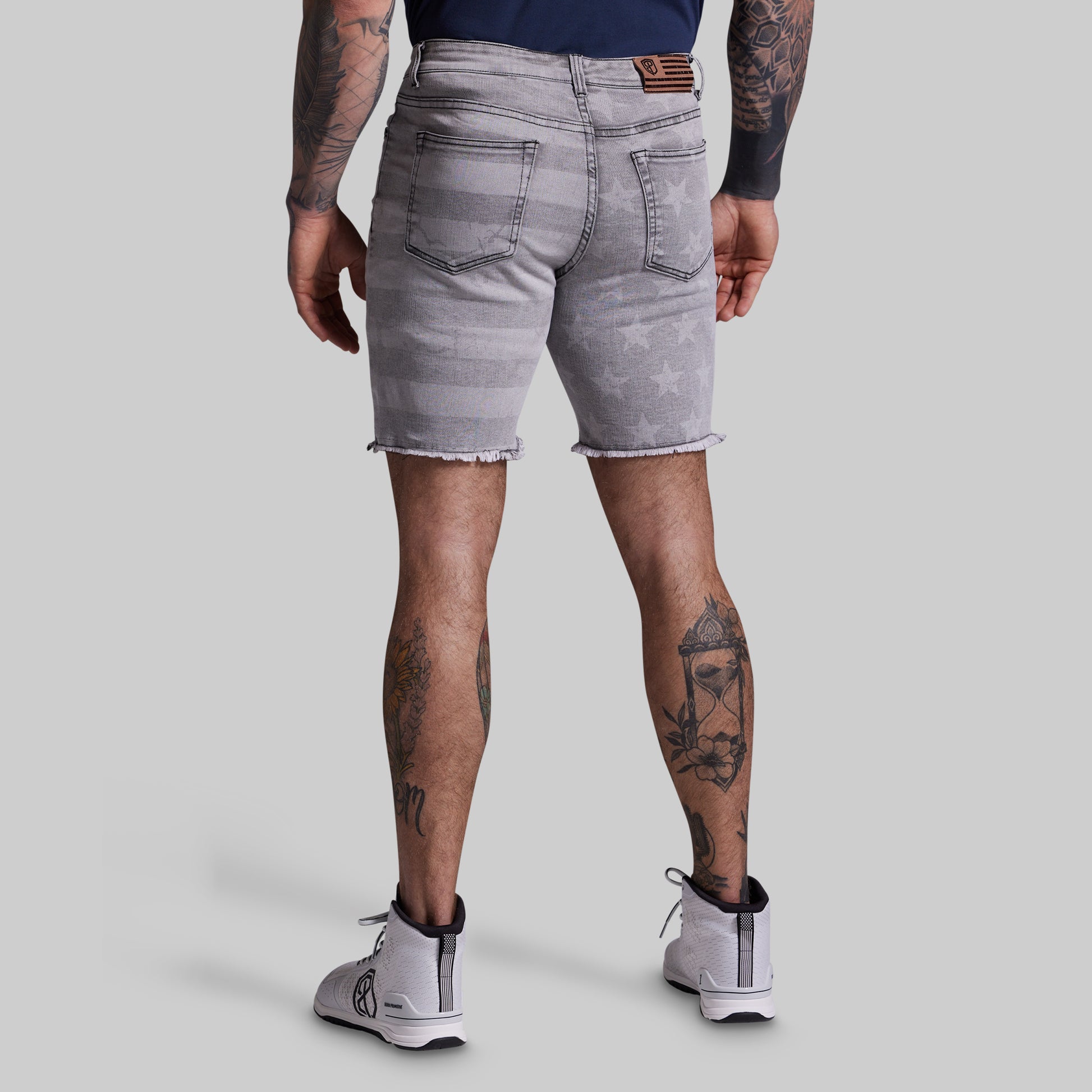 Person wearing gray denim shorts on a plain background