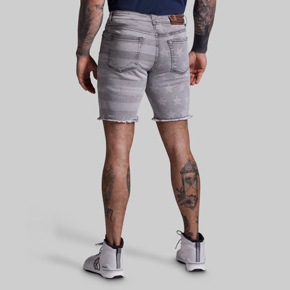 Person wearing gray denim shorts on a plain background