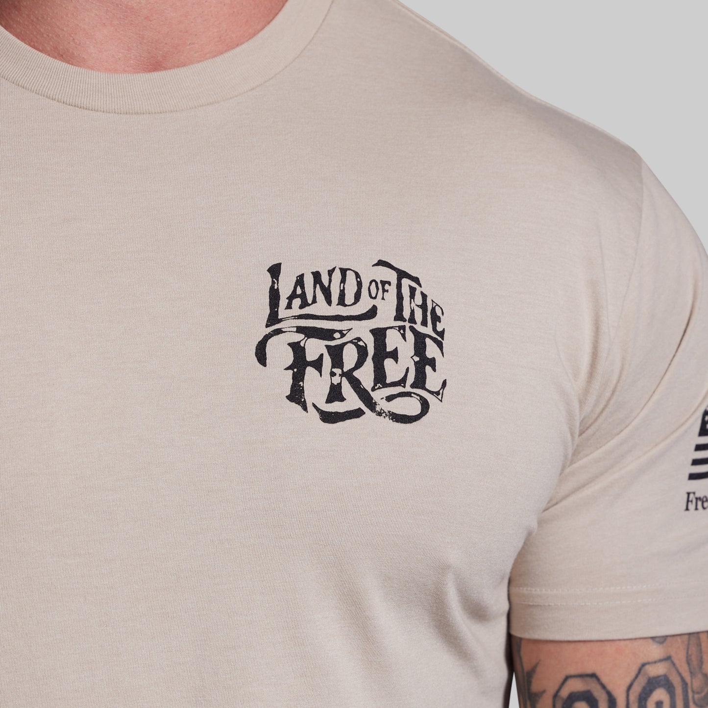Beige t-shirt with 'Land of the Free' text on a plain background