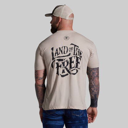Man wearing a beige t-shirt with 'Land of the Free' text on the back, standing against a plain background.