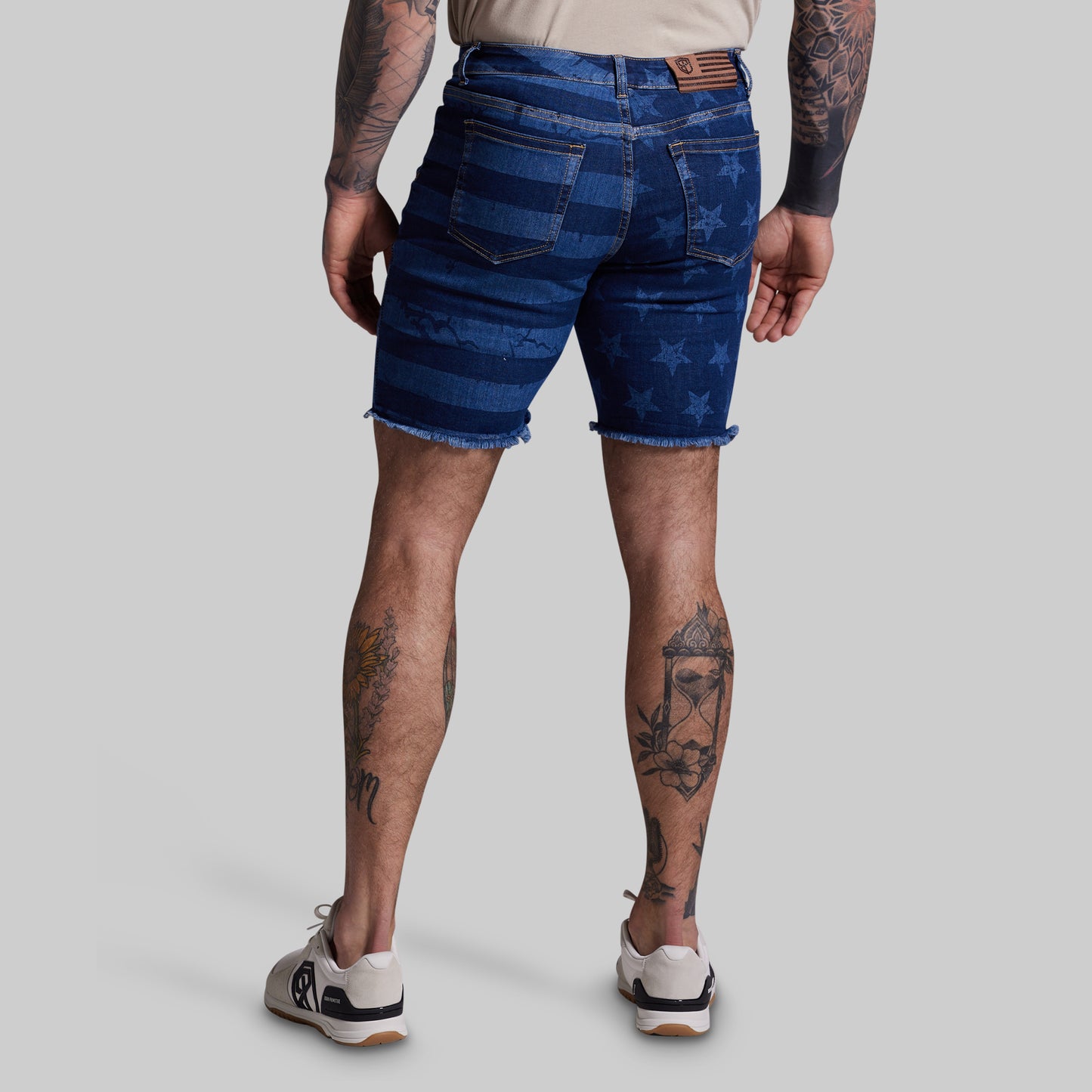 Person wearing blue denim shorts with star pattern on a plain background
