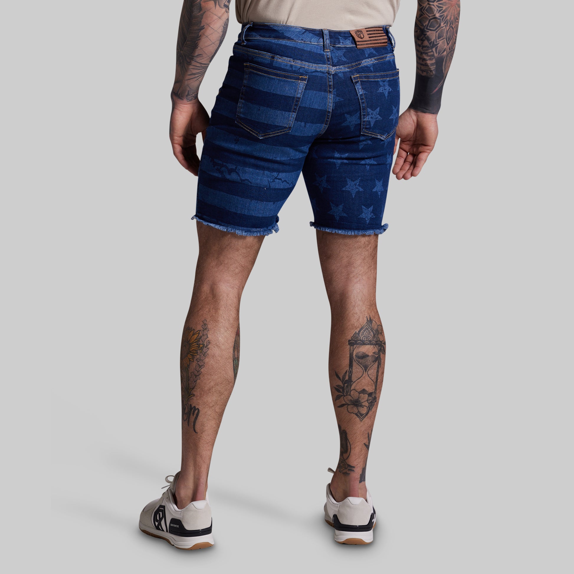 Person wearing blue denim shorts with star pattern on a plain background