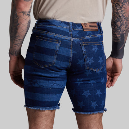 Person wearing blue denim shorts with star pattern on a plain background