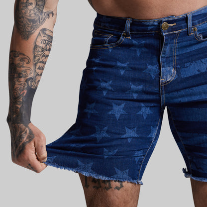 Person wearing blue denim shorts with star pattern on a plain background