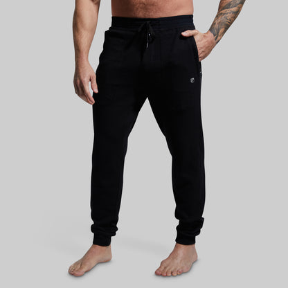 Person wearing black jogger pants on a gray background