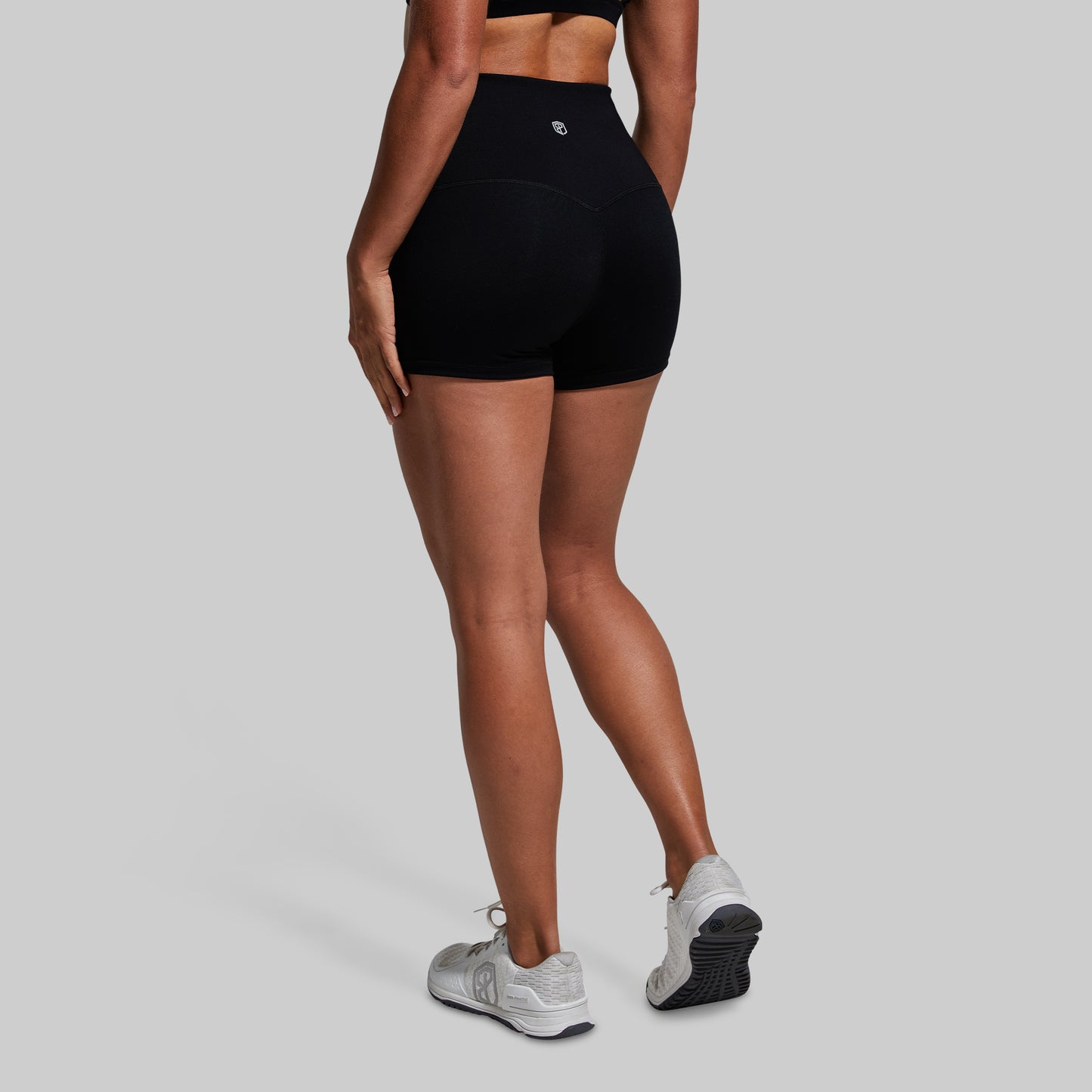 Person wearing black high-waisted shorts on a gray background