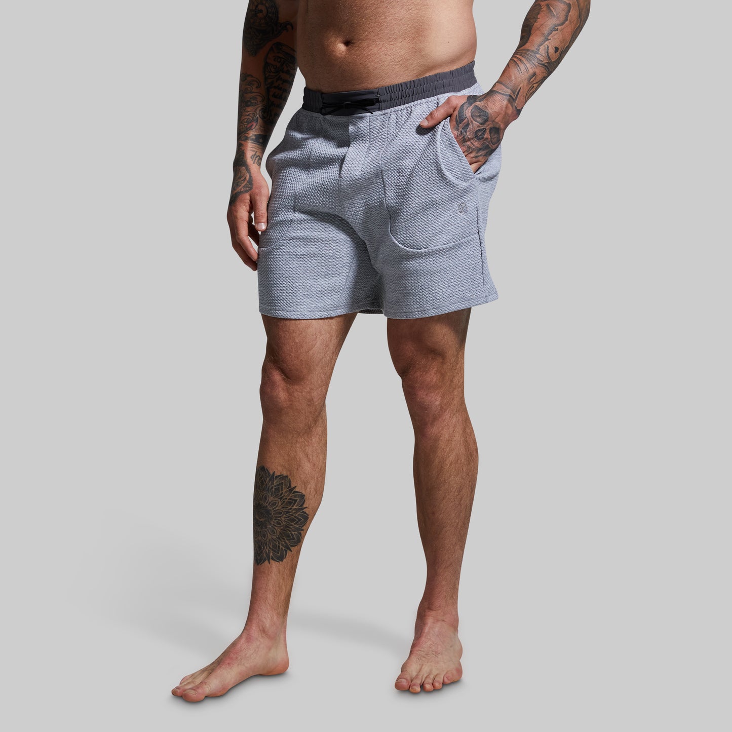 Person wearing light gray patterned shorts on a plain background