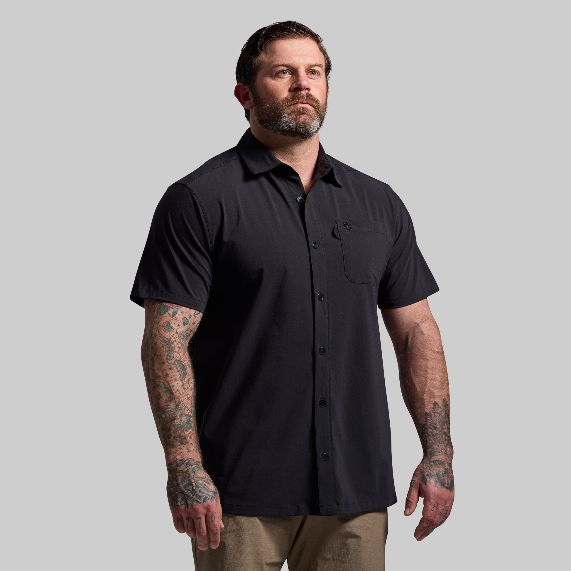 Man wearing a black short-sleeve shirt against a gray background