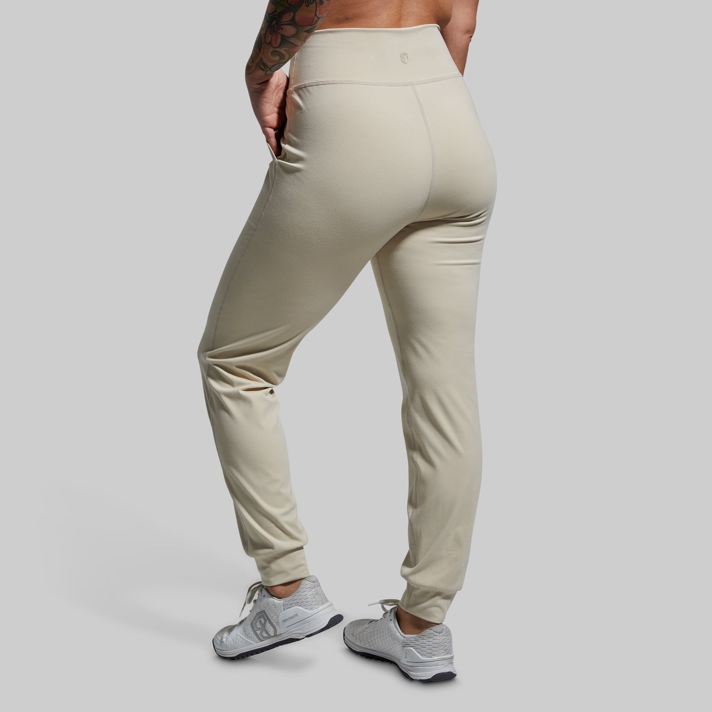 Beige jogger pants worn by a person on a gray background
