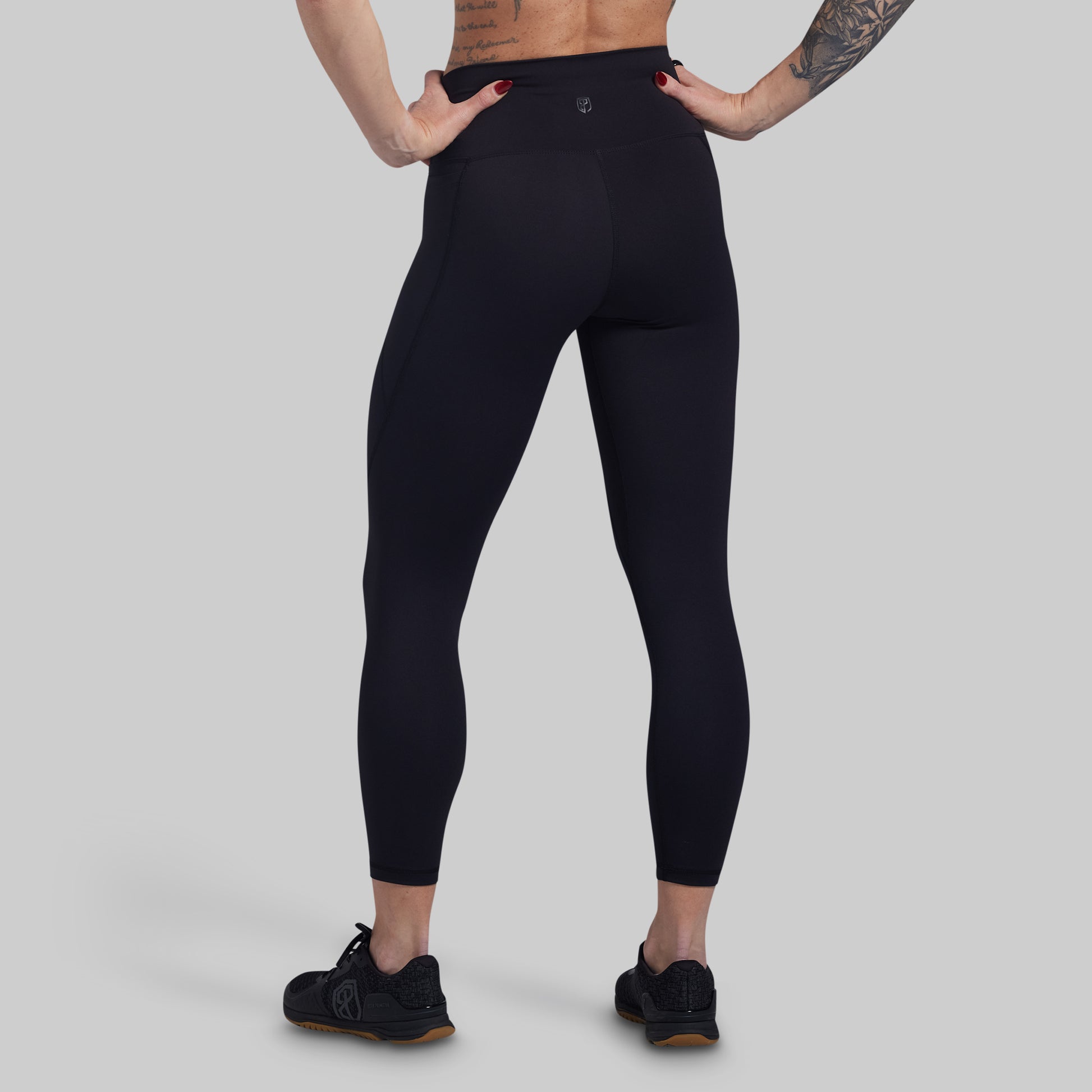 Person wearing black leggings on a gray background