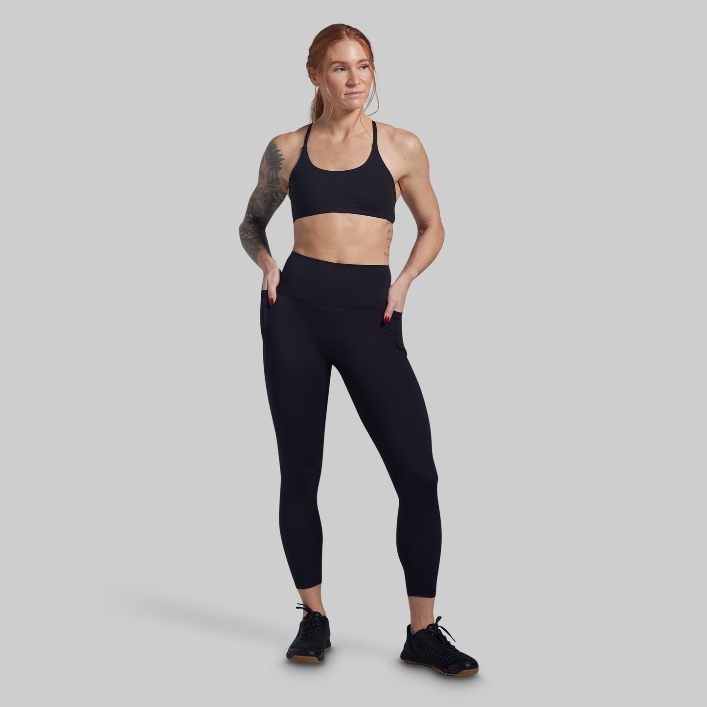 Woman wearing a black sports bra and leggings on a gray background