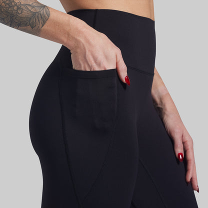 Person wearing black leggings with a plain background