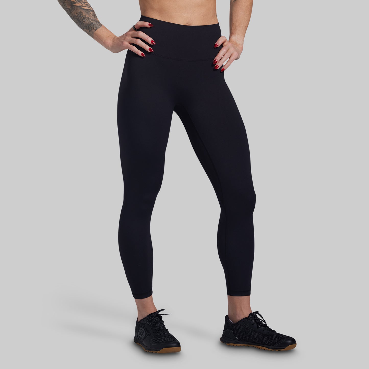 Person wearing black leggings on a gray background