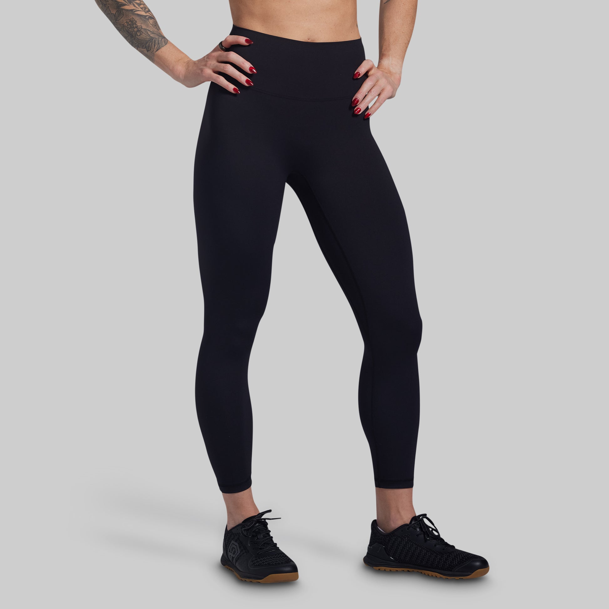 Person wearing black leggings on a gray background