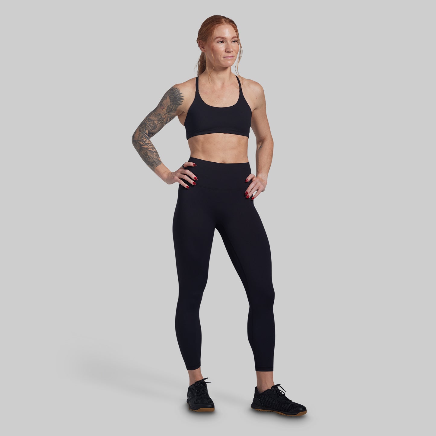 Woman wearing a black sports bra and leggings on a gray background