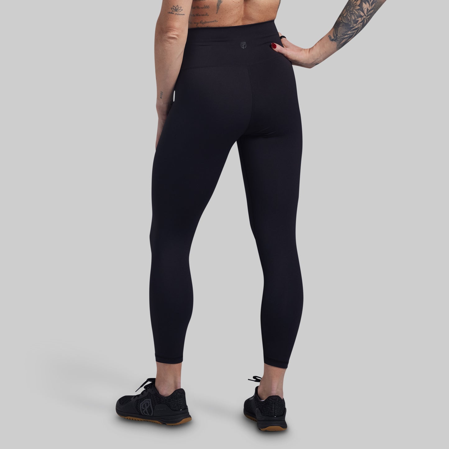 Person wearing black leggings on a gray background