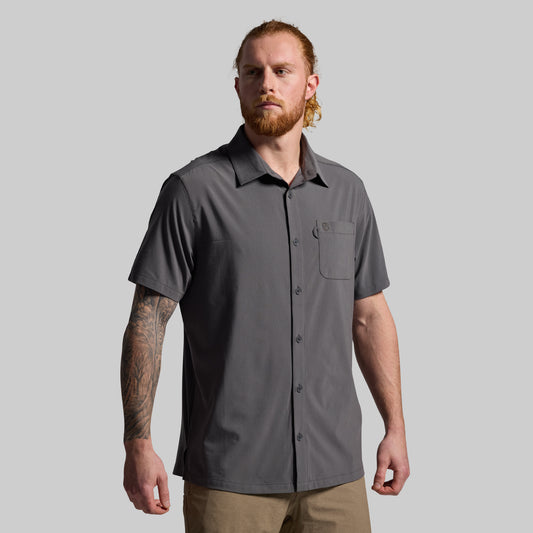 Man wearing a gray short-sleeve shirt on a plain background
