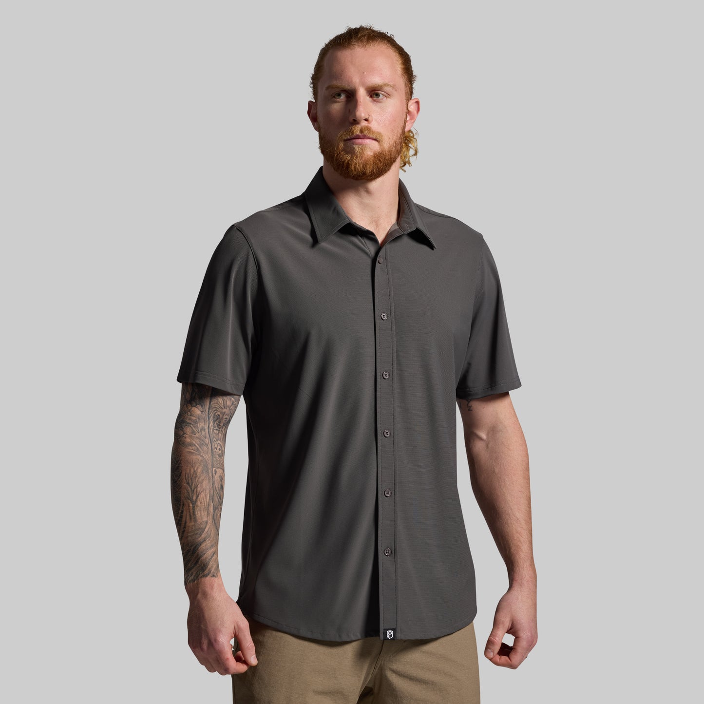 Man wearing a gray short-sleeve shirt against a plain background