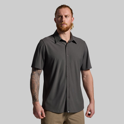 Man wearing a gray short-sleeve shirt against a plain background