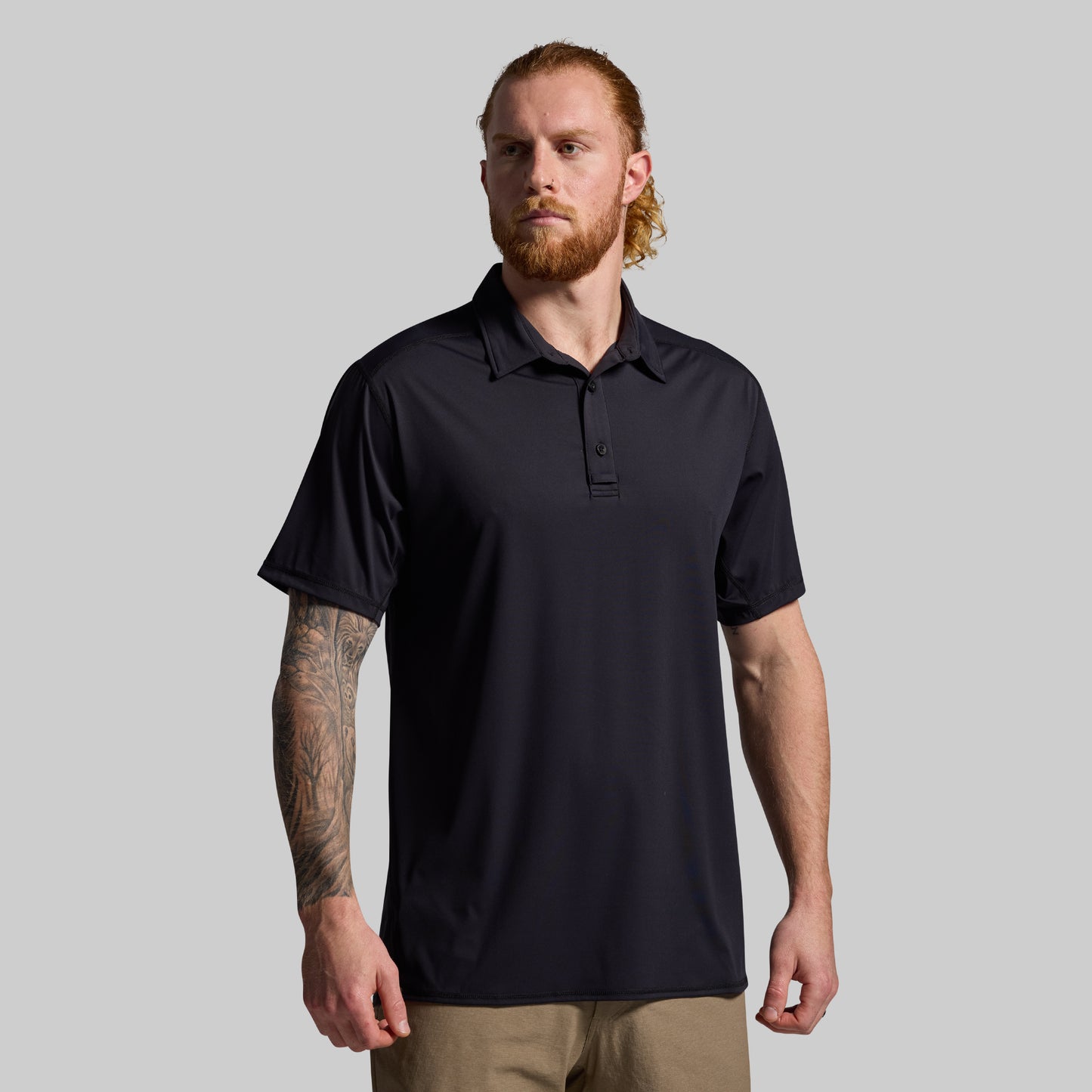Man wearing a black polo shirt against a gray background