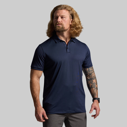 Man wearing a navy blue polo shirt against a gray background