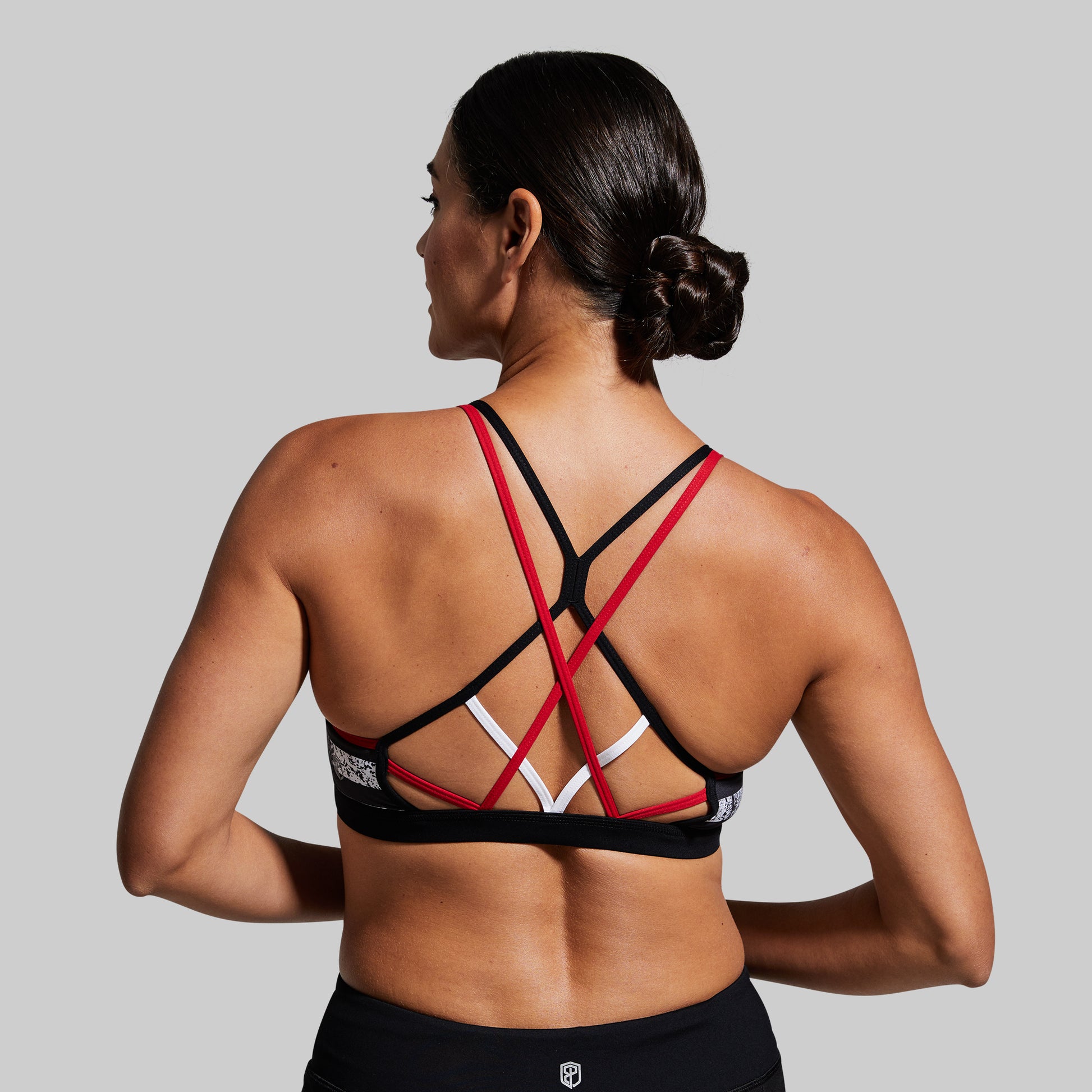 Person wearing a black sports bra with red straps on a gray background