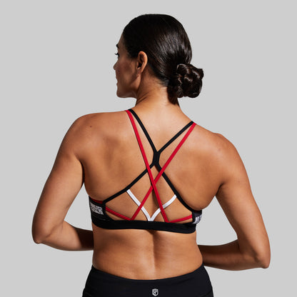Person wearing a black sports bra with red straps on a gray background