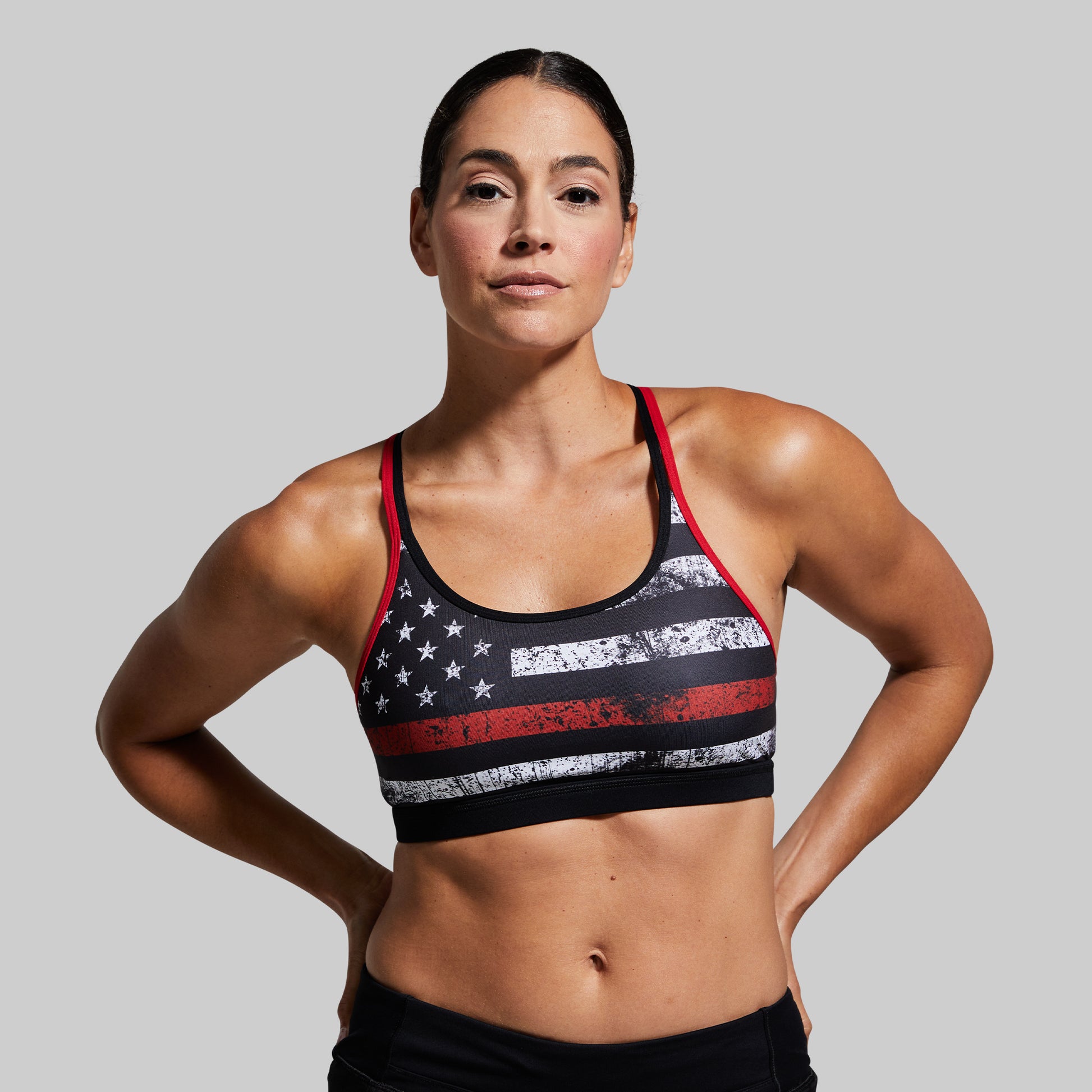 Woman wearing a sports bra with an American flag design on a gray background