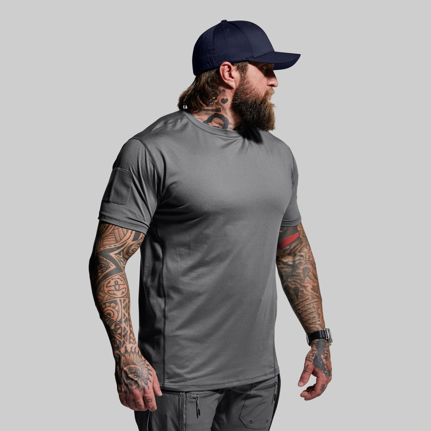 Man wearing a gray t-shirt and navy cap on a light gray background