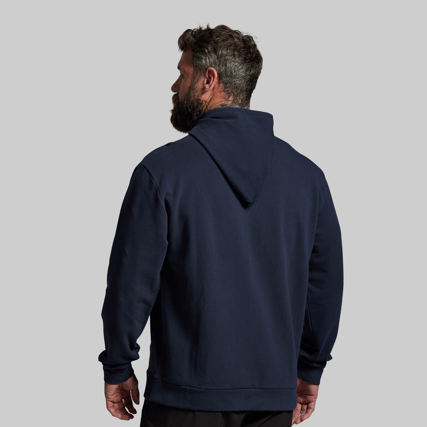 Man wearing a navy blue hoodie on a light gray background
