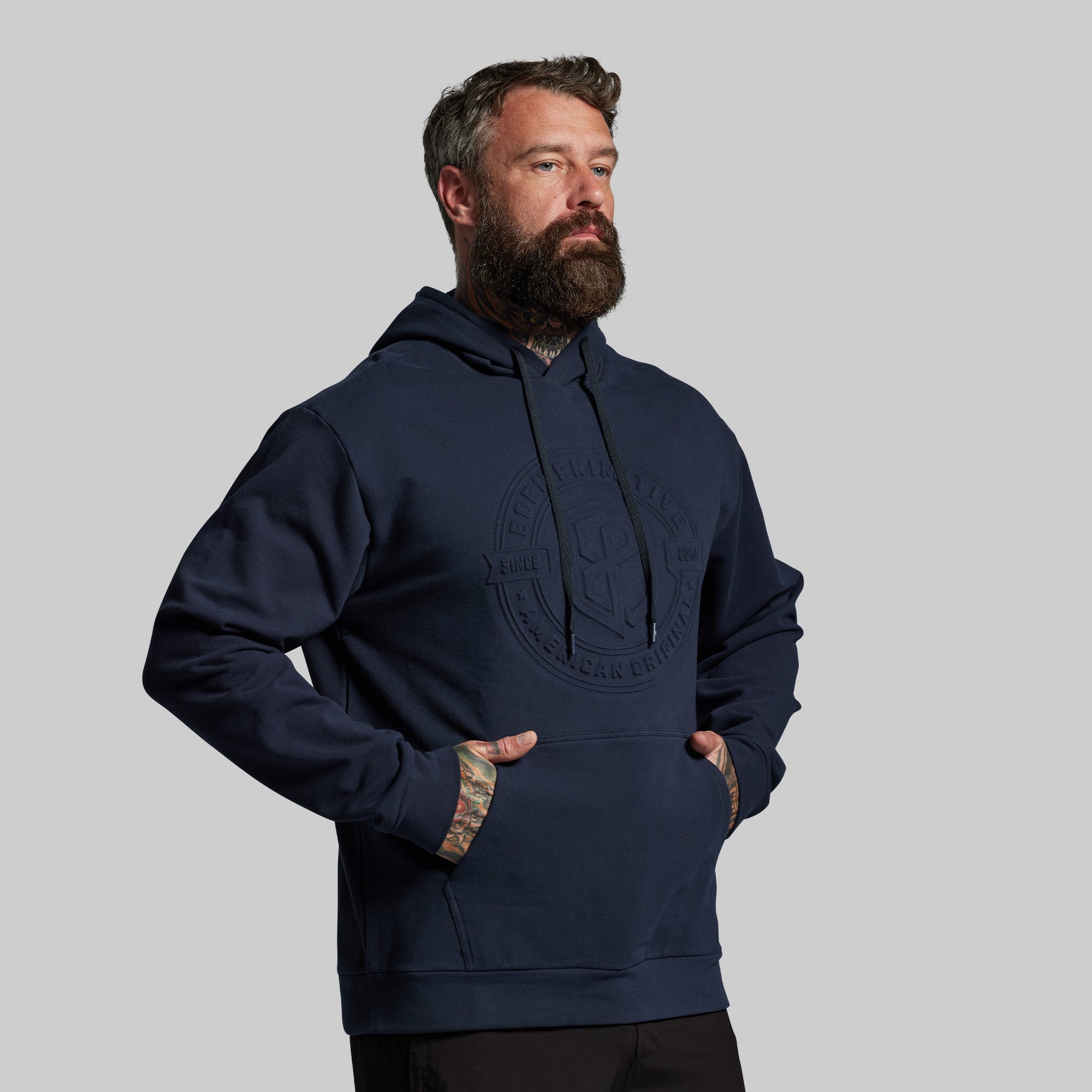 Man wearing a navy blue hoodie with a logo on a gray background