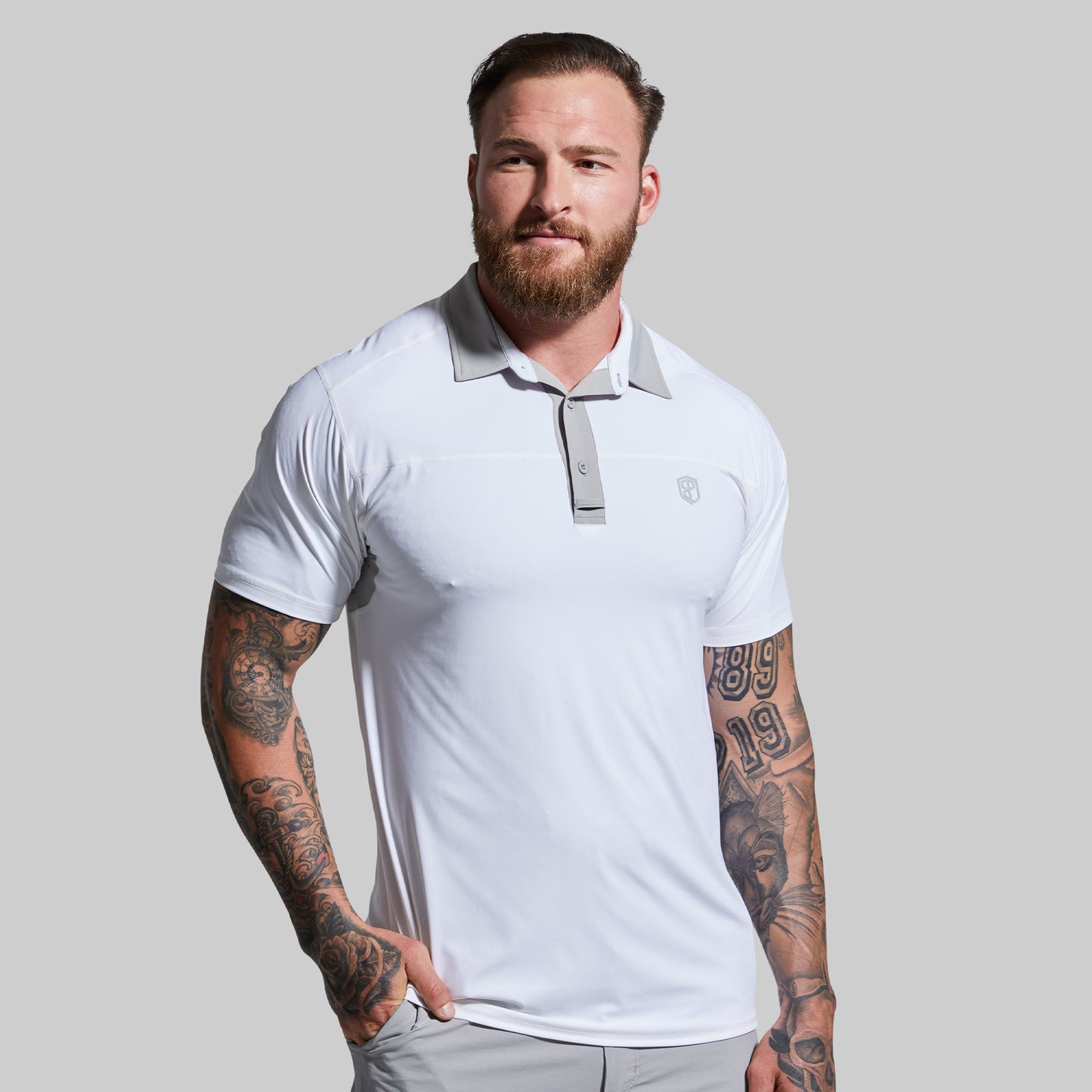 Man wearing a white polo shirt with a logo on a gray background