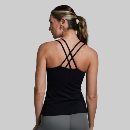Woman wearing a black tank top with criss-cross straps on a gray background