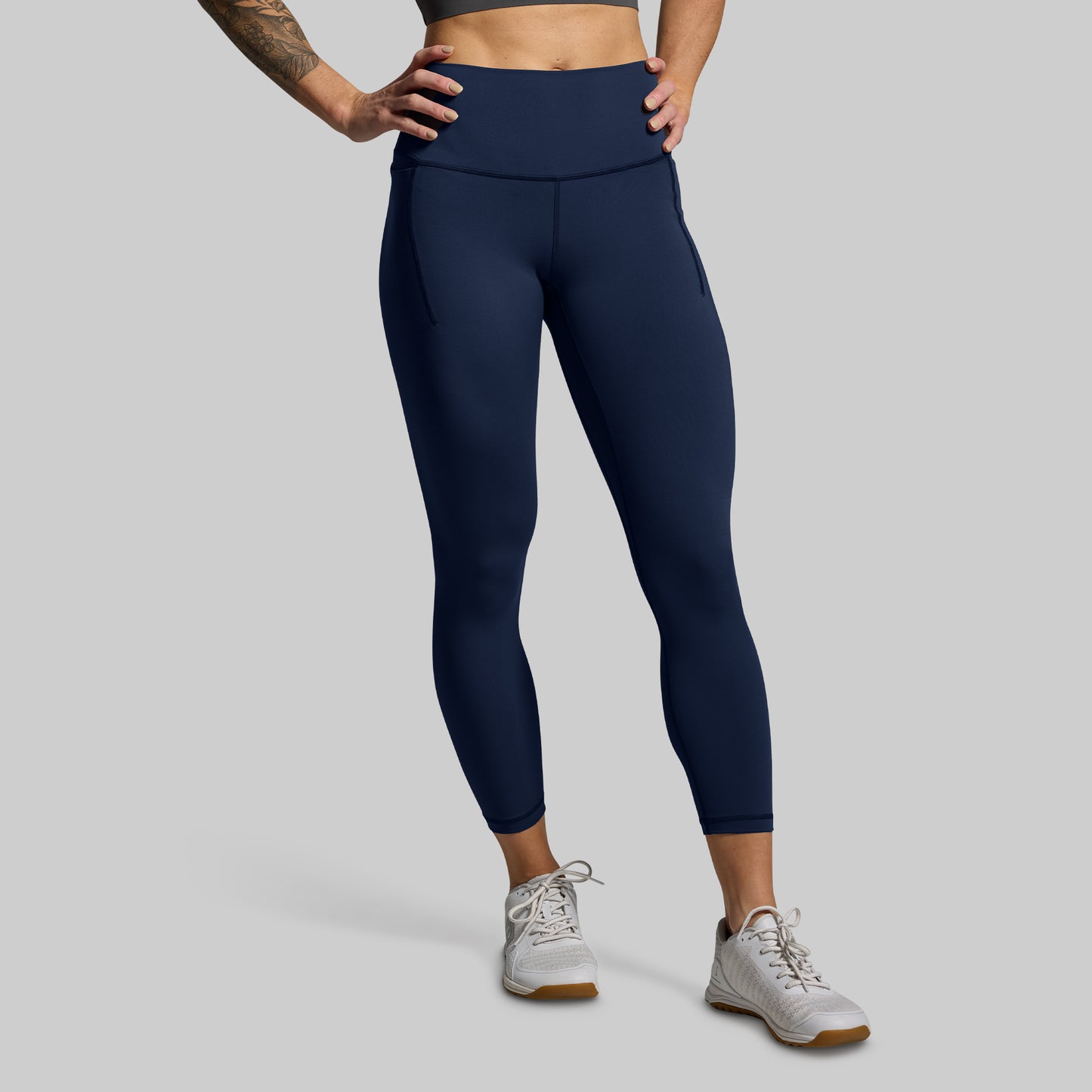 Person wearing dark blue leggings on a plain background