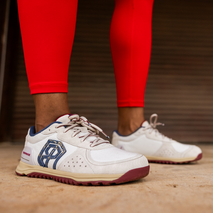 White sneakers with blue accents worn with red leggings on a wooden floor.